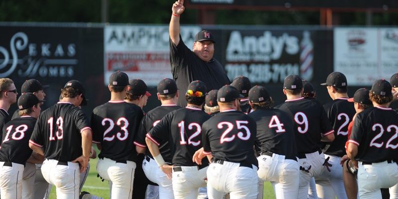 Photo of Coach Pudge with arm raised, celebrating victory with baseball team.