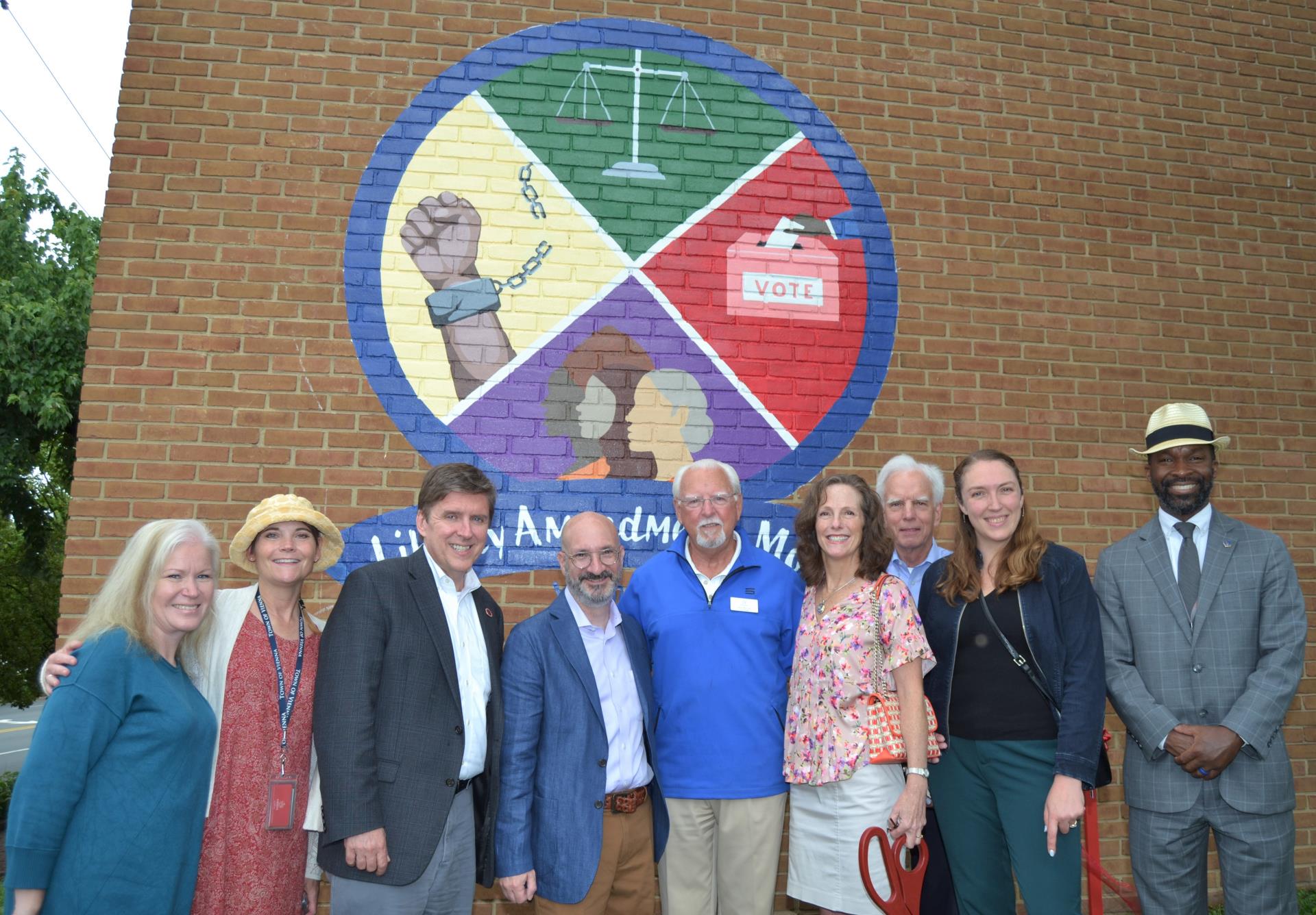 Group of people smiling and Mural unveiling event.